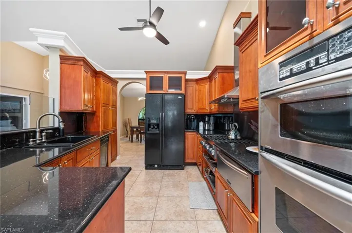 Kitchen with black refrigerator with ice dispenser, a sink, a warming drawer, dishwashing machine, and stainless steel double oven