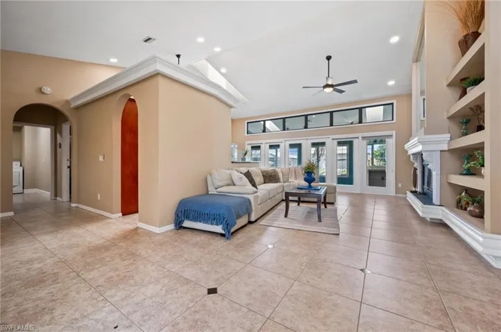 Living room with arched walkways, ceiling fan, light tile patterned floors, recessed lighting, and washer / dryer