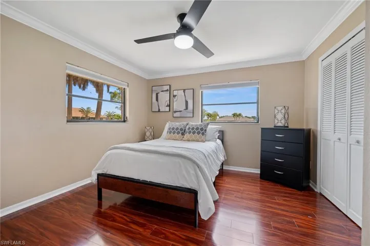 Bedroom with multiple windows, crown molding, dark wood finished floors, a closet, and baseboards