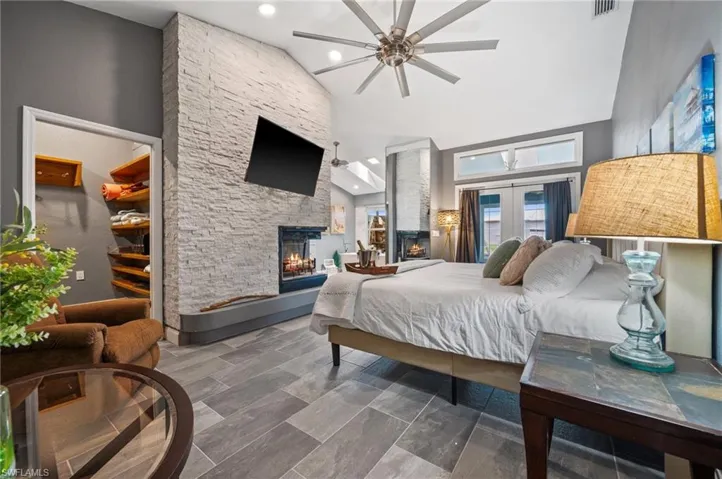 Bedroom with a fireplace, high vaulted ceiling, and recessed lighting