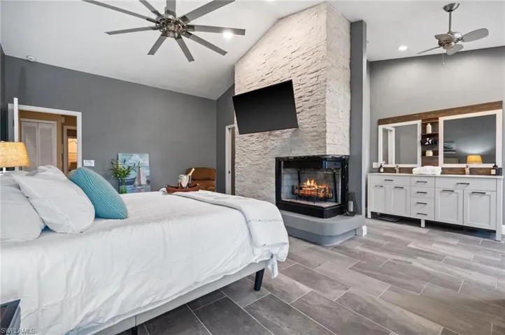 Bedroom featuring a fireplace, high vaulted ceiling, and a ceiling fan