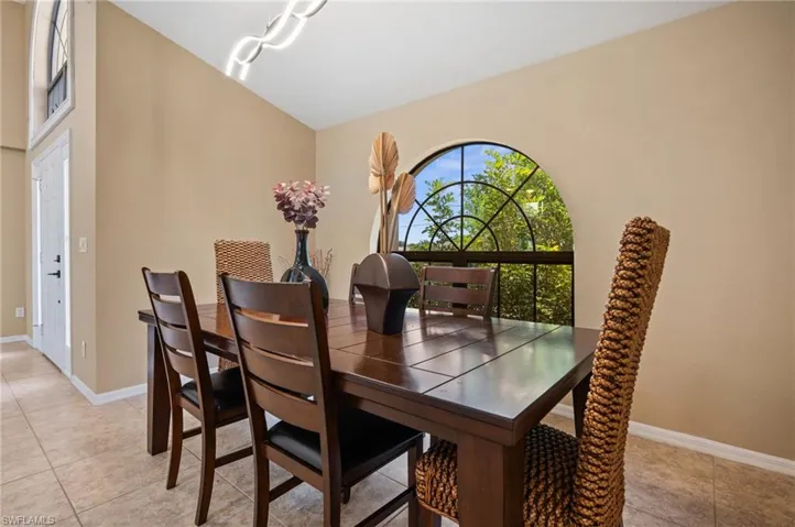 Dining room featuring light tile patterned floors, baseboards, and vaulted ceiling