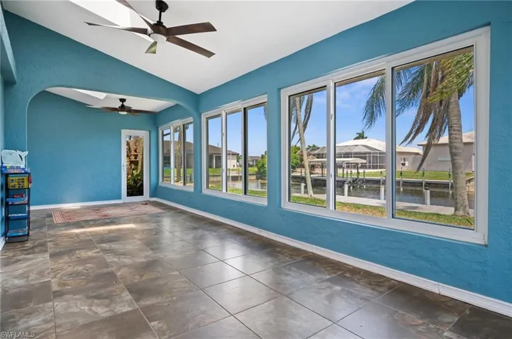 Empty room featuring a ceiling fan, lofted ceiling, healthy amount of natural light, baseboards, and a water view