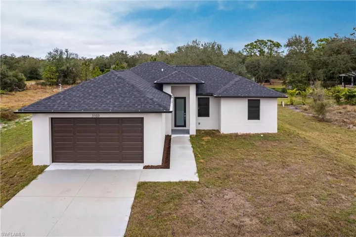 View of front of property with a garage and a front lawn