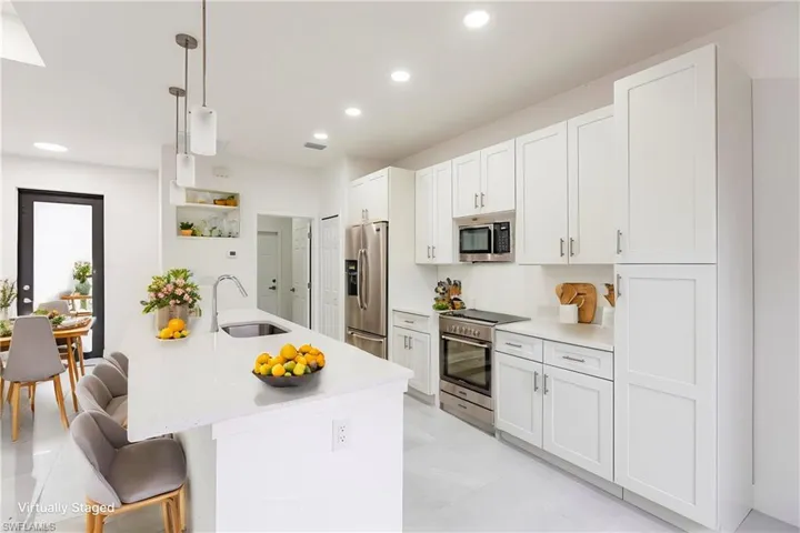 Kitchen featuring sink, hanging light fixtures, white cabinets, and appliances with stainless steel finishes
