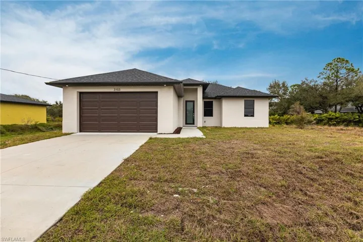 View of front of home with a garage and a front lawn