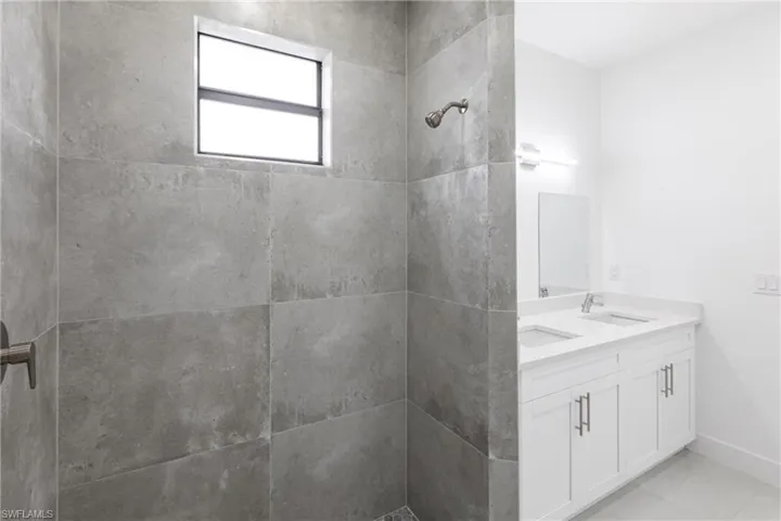Bathroom with vanity, a tile shower, and tile patterned flooring