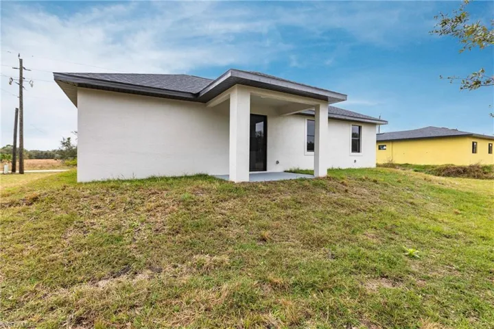Back of house with a patio area and a lawn