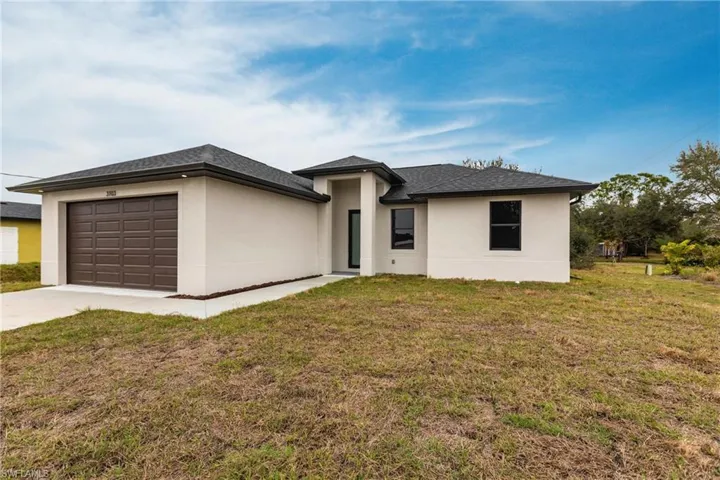 View of front of house with a garage and a front lawn