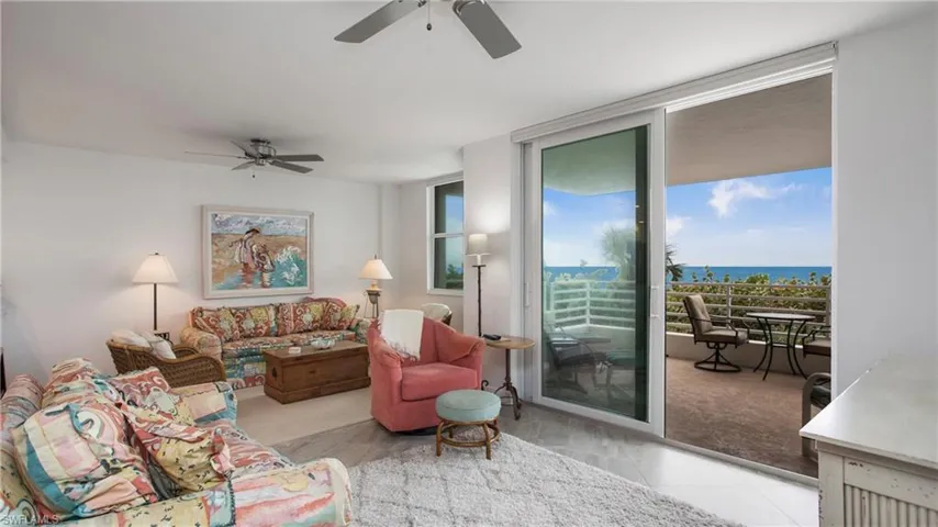 Living room with ceiling fan, a water view, light tile patterned floors, and a wall of windows