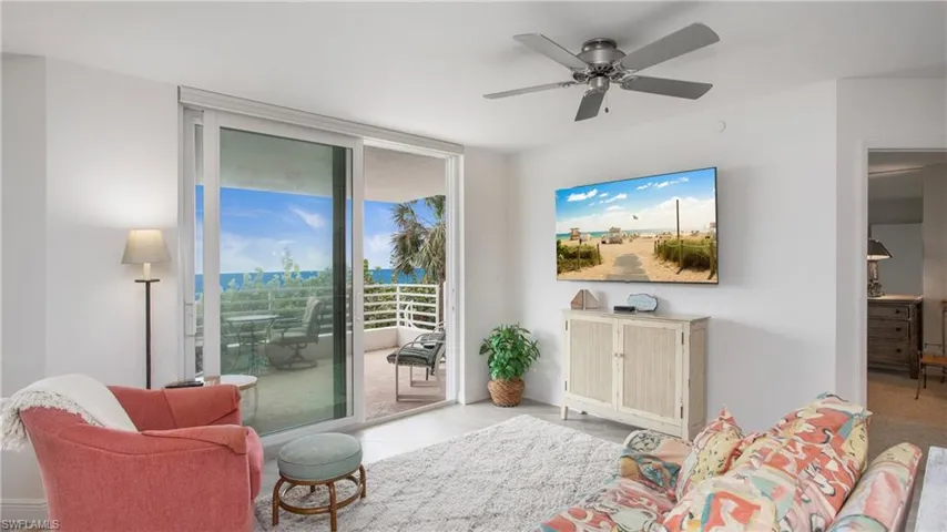 Living room featuring light tile patterned flooring, ceiling fan, and floor to ceiling windows