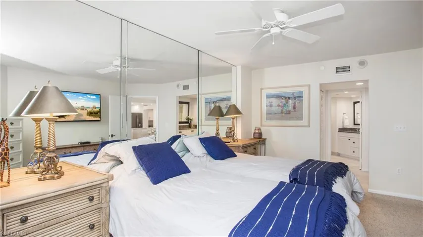 Carpeted bedroom featuring connected bathroom, ceiling fan, and a closet