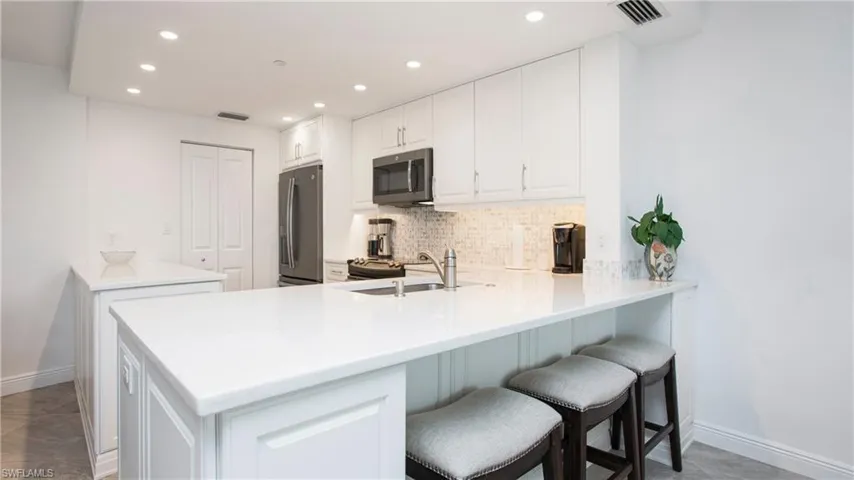 Kitchen featuring appliances with stainless steel finishes, kitchen peninsula, sink, and white cabinets
