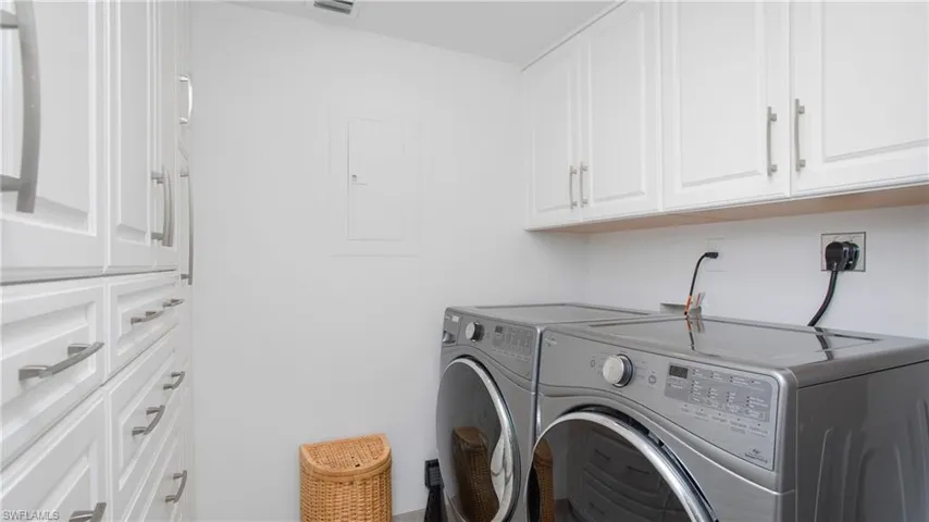 Laundry room featuring cabinets, electric panel, and washer and clothes dryer