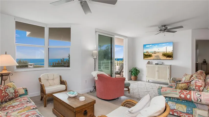 Living room with a water view, light colored carpet, and ceiling fan