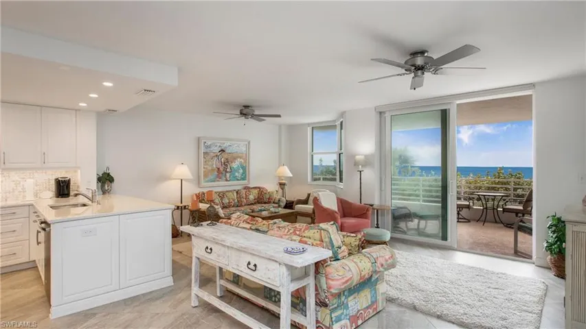 Living room with floor to ceiling windows, a water view, sink, and ceiling fan