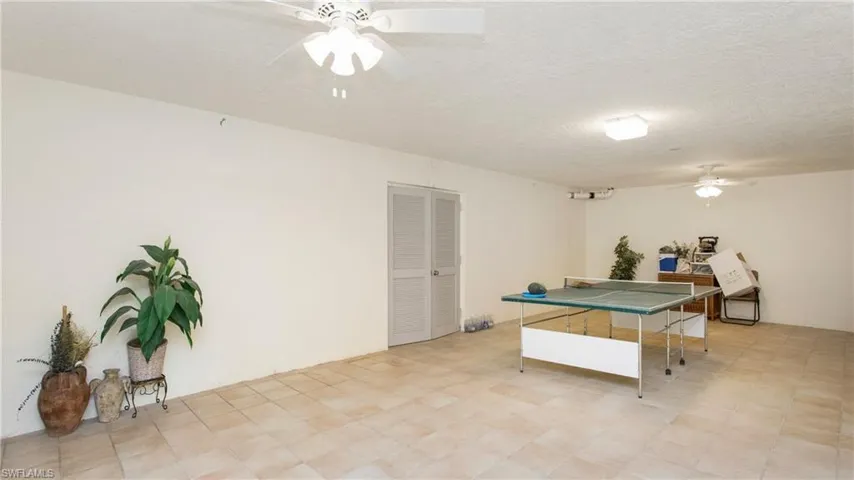 Rec room with ceiling fan and a textured ceiling