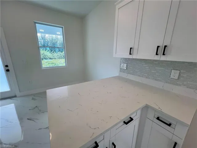 Kitchen featuring white cabinetry, tasteful backsplash, and light QUARTZ countertops
