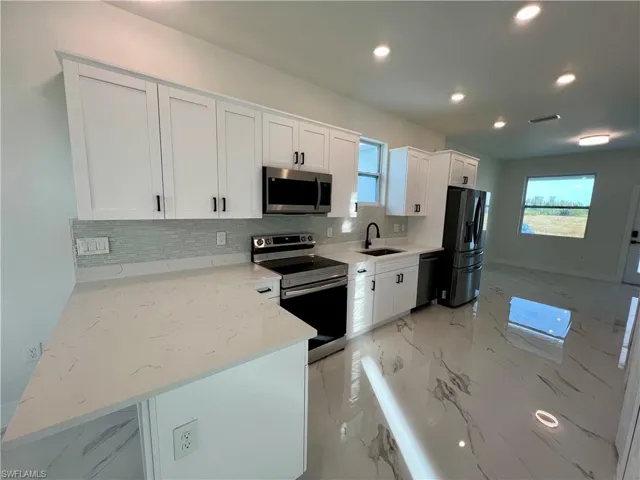 Kitchen with appliances with stainless steel finishes, white cabinetry, plenty of natural light, and light QUARTZ counters