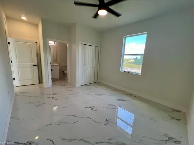 Primary bedroom with a closet, ceiling fan, and connected bathroom