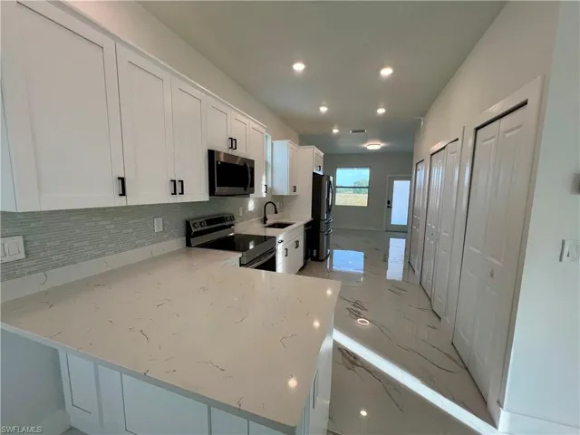 Kitchen featuring a breakfast bar, white cabinetry, and stainless steel appliances