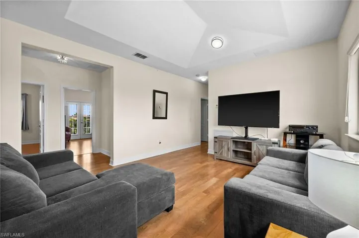 Living room with french doors, hardwood / wood-style flooring, and a raised ceiling