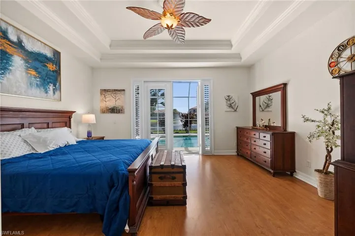Master Bedroom with crown molding, access to outside, a tray ceiling, ceiling fan, and wood-type flooring