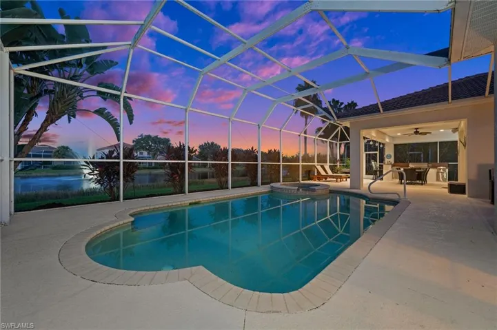 Pool at dusk featuring an in ground hot tub, a patio area, ceiling fan, and screen enclosure