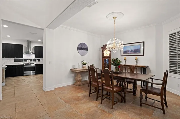 Tiled dining room with an inviting chandelier and crown molding