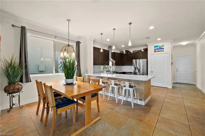 Dining room with ornamental molding, sink, light tile patterned flooring, and a chandelier