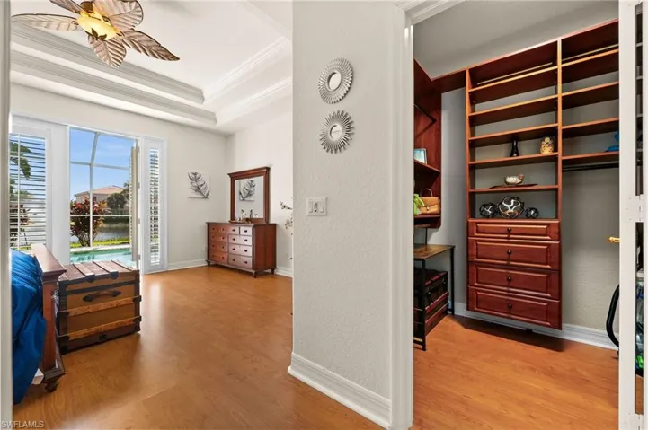 Spacious closet with ceiling fan, light hardwood / wood-style floors, and a tray ceiling