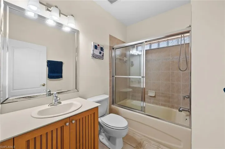 Full bathroom featuring tile patterned floors, vanity, combined bath / shower with glass door, and toilet