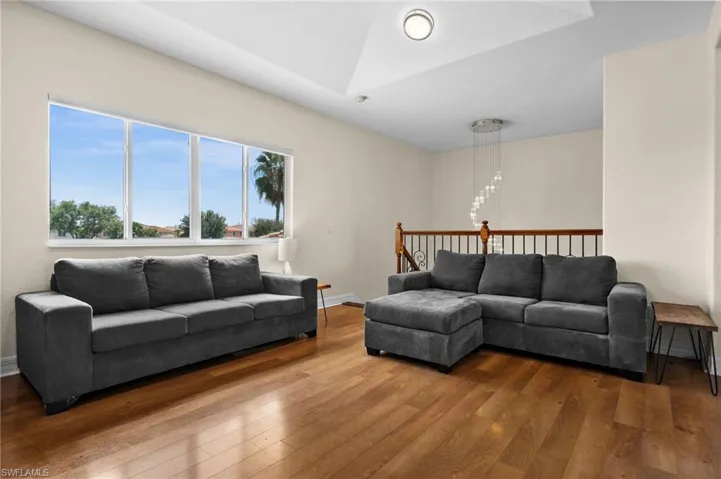 UPSTAIRS! Additional Living room area featuring an inviting chandelier, lofted ceiling, and wood-style flooring