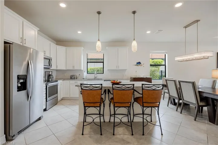 Kitchen featuring stainless steel appliances, sink, pendant lighting, white cabinets, and a kitchen island