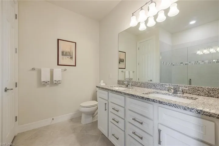 Bathroom featuring toilet, tile patterned flooring, walk in shower, and vanity