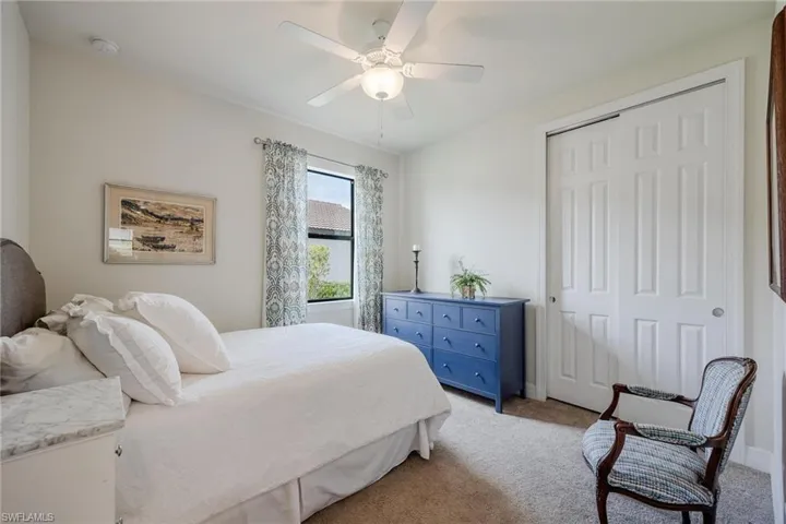 Carpeted bedroom featuring ceiling fan and a closet