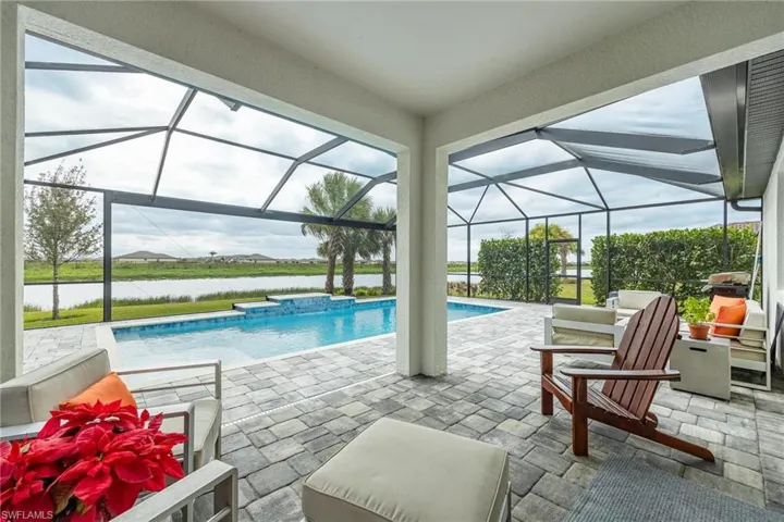 View of swimming pool with glass enclosure and a patio area
