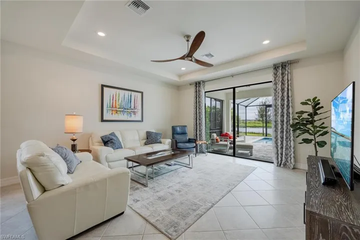 Tiled living room featuring ceiling fan and a raised ceiling