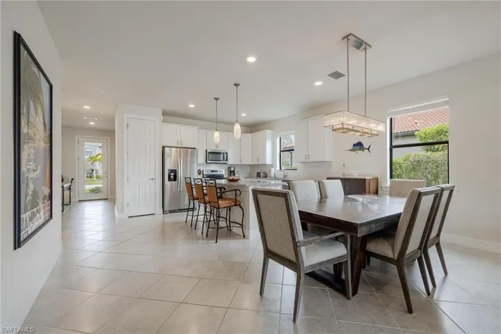 Tiled dining space with sink, a healthy amount of sunlight, and a chandelier