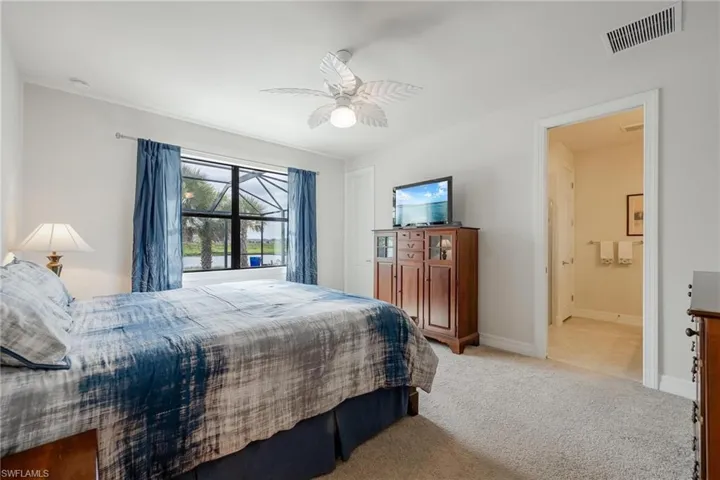 Bedroom with ceiling fan, ensuite bathroom, and light tile patterned floors