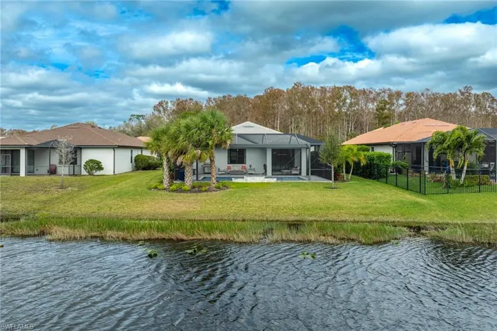 Rear view of property with a patio, a lawn, and a water view