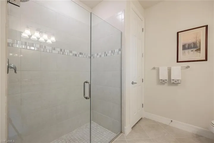 Bathroom featuring tile patterned flooring, an enclosed shower, and toilet