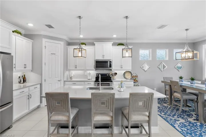 Kitchen featuring a kitchen breakfast bar, a kitchen island with sink, pendant lighting, and stainless steel appliances
