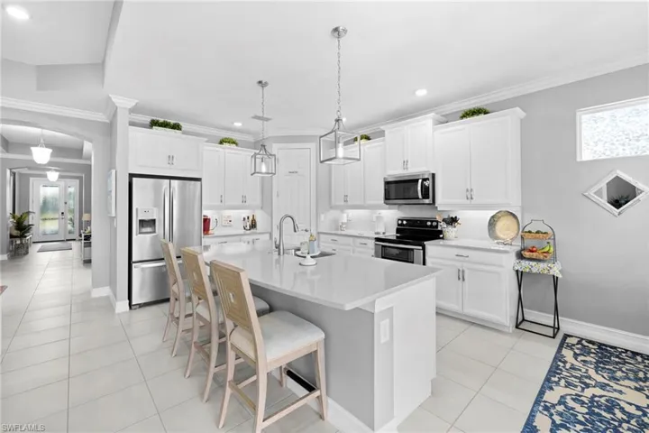Kitchen featuring a breakfast bar area, sink, stainless steel appliances, and ornamental molding