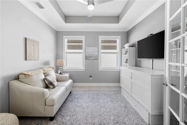 Living area featuring ceiling fan, crown molding, and a tray ceiling