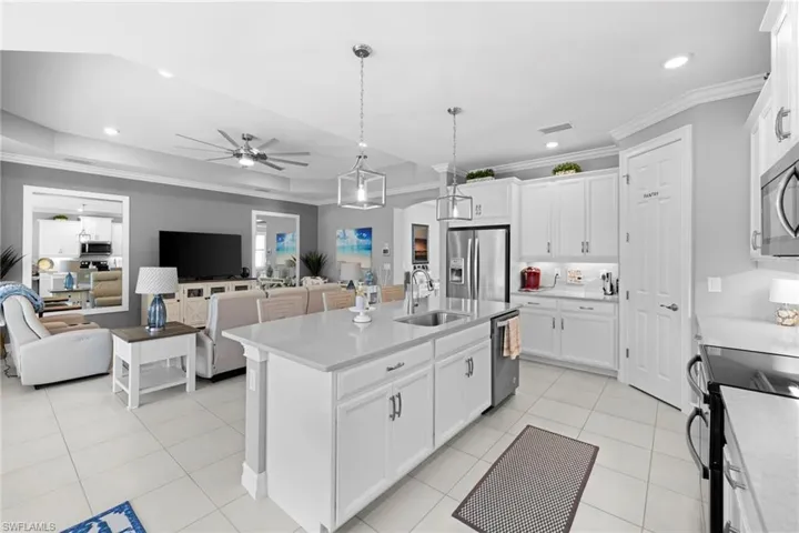 Kitchen with white cabinetry, sink, crown molding, a center island with sink, and appliances with stainless steel finishes