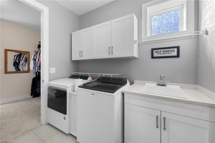 Laundry room with cabinets, independent washer and dryer, light tile patterned floors, and sink