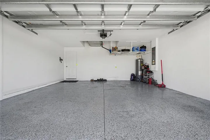 Garage with water heater, electric panel, and a garage door opener