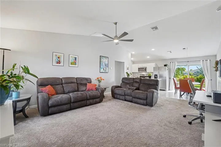 Carpeted living room featuring vaulted ceiling and ceiling fan