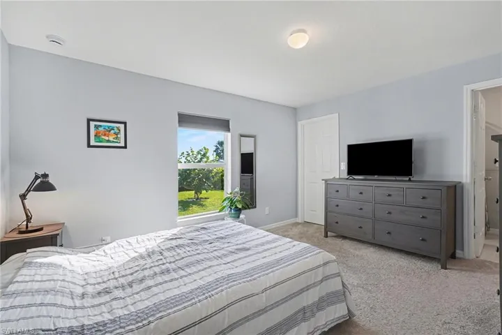 Bedroom featuring light colored carpet and connected bathroom